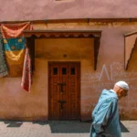 A man walks by doors and rugs.