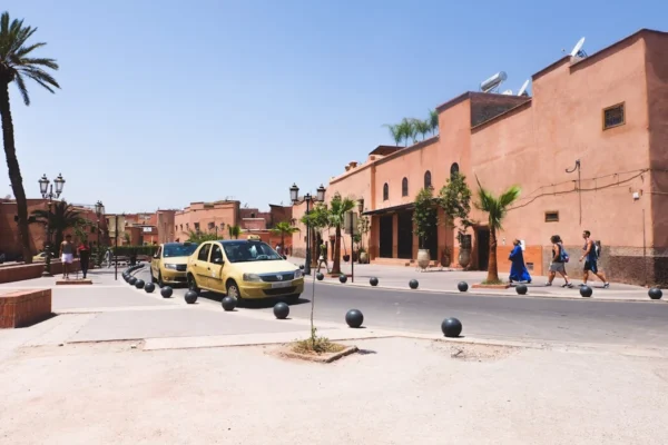 Yellow taxis drive down a sunny street in morocco.